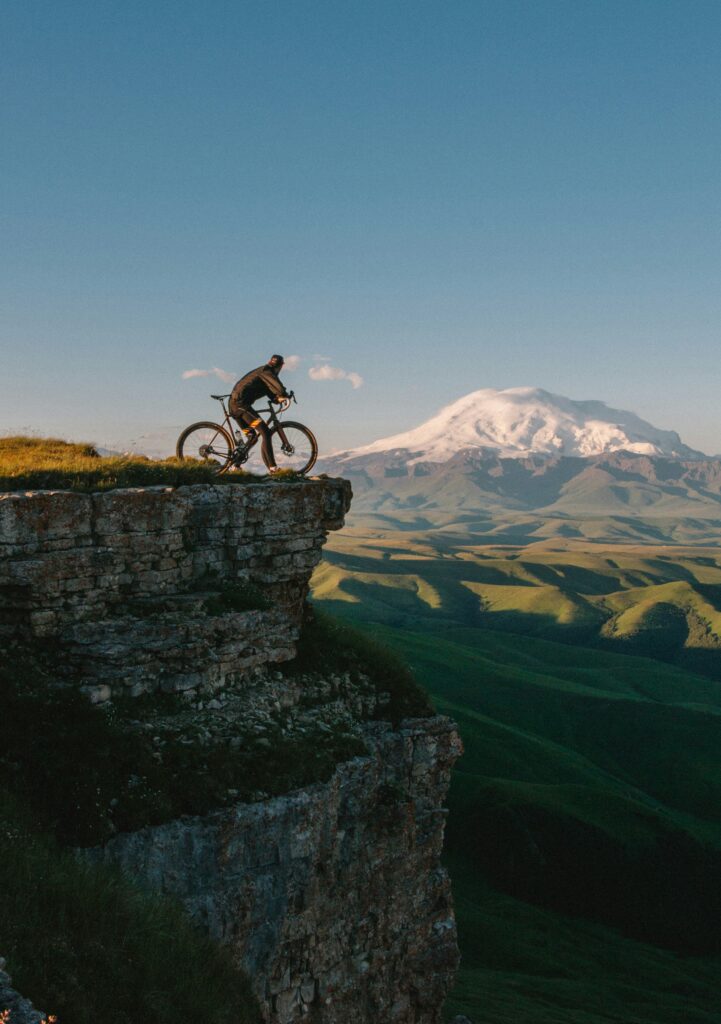 A man on a bicycle at the end of a mountain with enchanting natural landscape