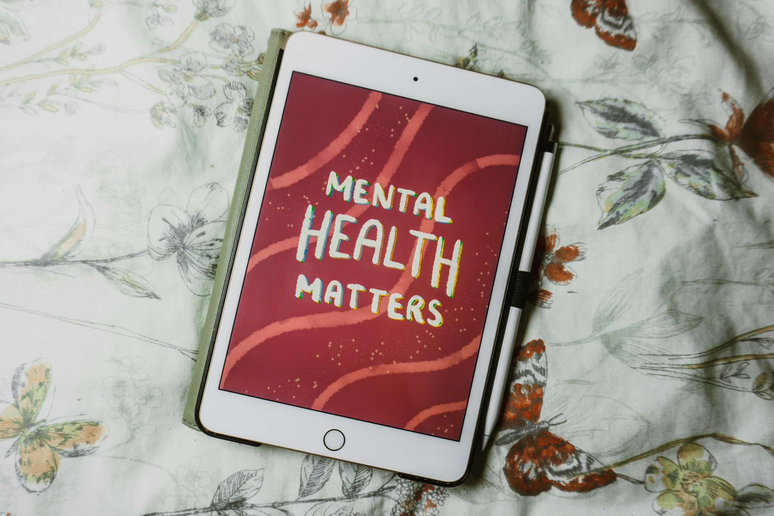 A tablet lies on the bed and on the screen is written mental health matters