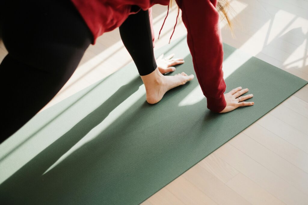 A foot and two hands of a woman on a yoga mat
