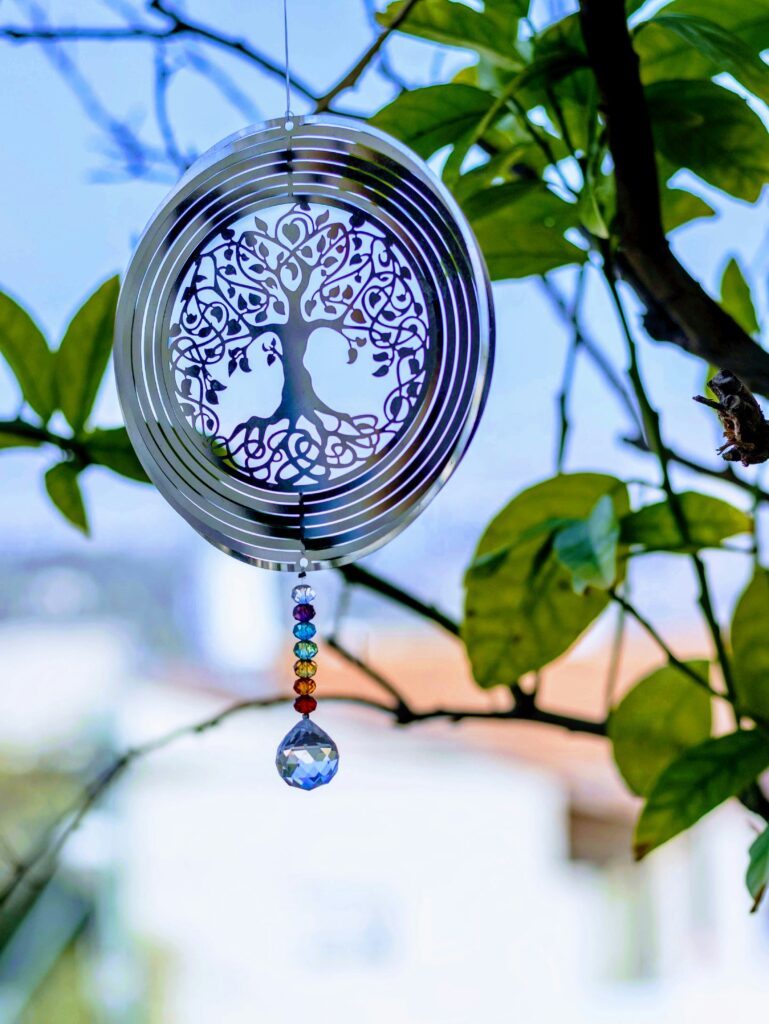 A round metal pendant hangs on the tree between green leaves