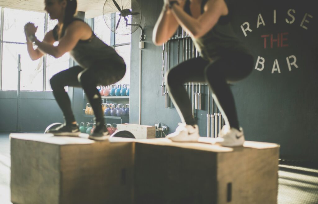 Two women doing knee exercises on wooden boxes